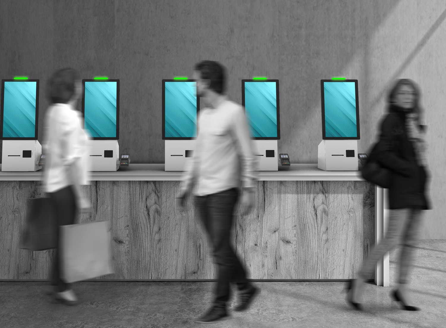 Trois personnes passent devant une rangée de cinq kiosques en libre-service dotés d'écrans bleus vierges dans un environnement intérieur moderne.